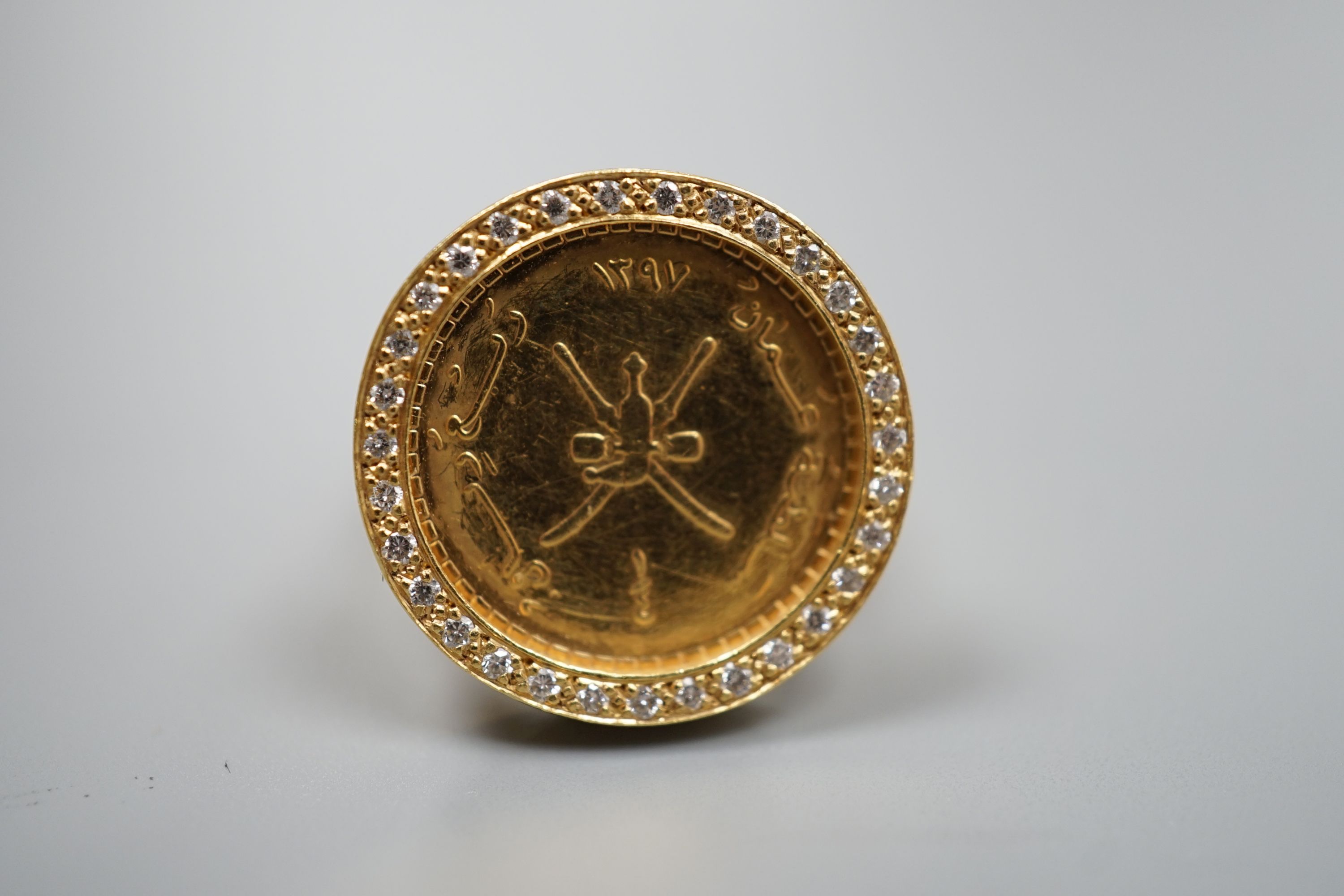 A 20th century Middle Eastern yellow metal and diamond chip set dress ring, inset with Middle Eastern yellow metal coin, size N